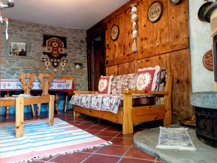 Living room with rustic sofa, wooden coffee table, alpine panels and ceramic plates